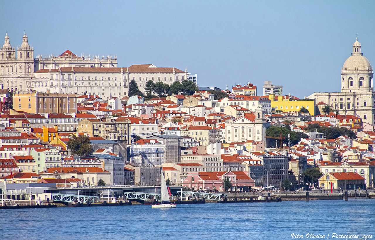 Lisbon seen across the Tagus: rooftops below the National Pantheon dome, with the river and the waterfront in the foreground.
